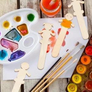 Unbehandelte menschen geformte Holz Bastelstäbe mit Farben und Pinsel für DIY-Projekte.
