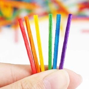 Bunte, dünne Holzstäbchen in der Hand, Bastelstäbchen für Kinder.