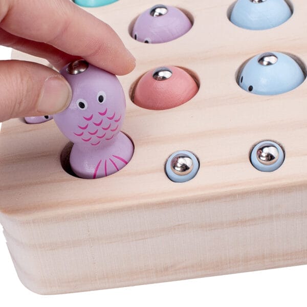 Jeu de pêche magnétique en bois pour enfants. L'enfant place une pieuvre violette sur le plateau.