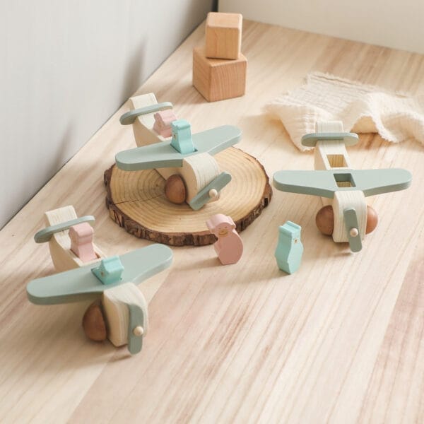 Drei pastellfarbene Holzflugzeuge mit kleinen Tierfiguren, ideales Lernspielzeug für Kinder.