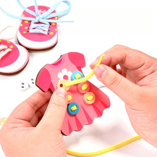 Mains d'enfant enfilant des lacets dans une robe et des chaussures en bois.