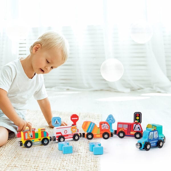 Un enfant joue avec un train en bois coloré. Les wagons comprennent une ambulance, un camion de pompiers et une voiture de police.