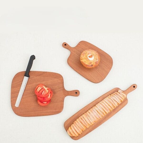 Drei Schneidebretter aus Holz: eines mit geschnittenen Tomaten, eines mit Gebäck und eines mit geschnittenem Brot. Perfekt für Küche und Tisch.