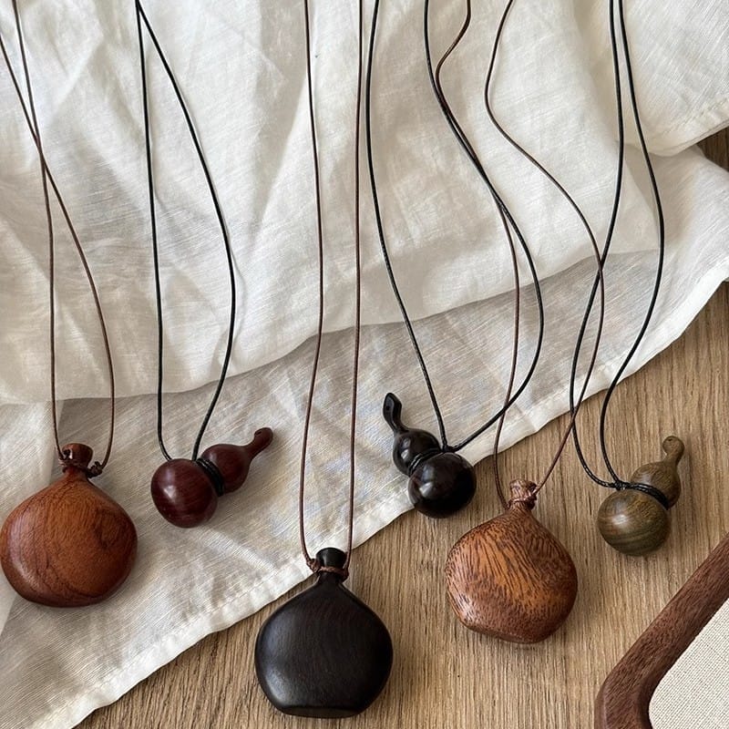 Halsketten mit Holzanhängern in verschiedenen Formen und dunklen Holztönen.