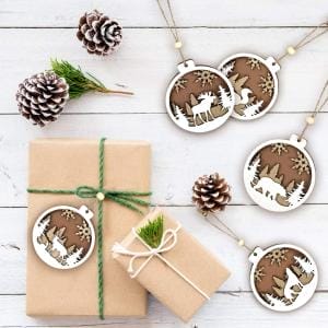 Holz Tierornamente: Runde Weihnachtsbaum-Anhänger mit Tiermotiven, Geschenkverpackung und Tannenzapfen.