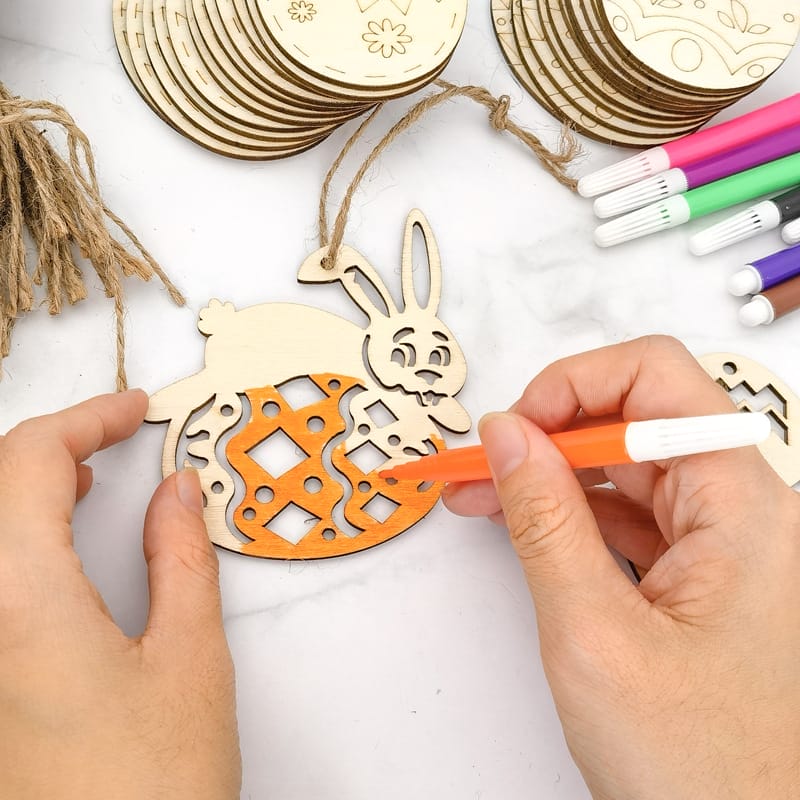 Person, die hölzerne Osterhasen-Ornamente mit Juteschnur bemalt. Großhandels-Osterhasen-Holzausschnitte.