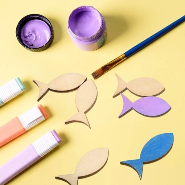 Hölzerne Fischformen, Farbe und Marker, bereit für ein DIY-Bastelprojekt. Großhandels-Fischausschnitte aus Holz, ideal für kreative Projekte.