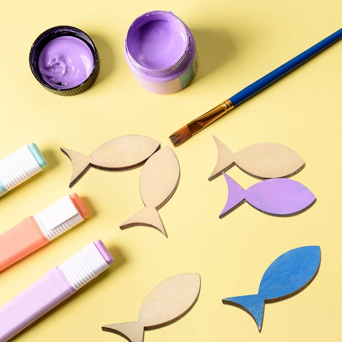 Hölzerne Fischformen, Farbe und Marker, bereit für ein DIY-Bastelprojekt. Großhandels-Fischausschnitte aus Holz, ideal für kreative Projekte.
