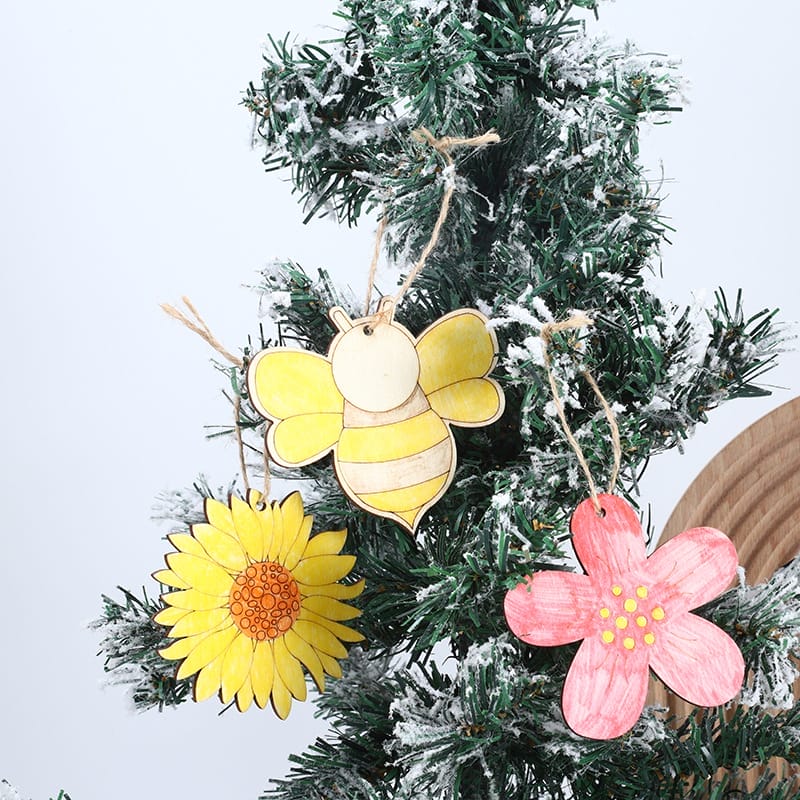 Hölzerne Bienen-, Sonnenblumen- und Blumenornamente hängen an einem Weihnachtsbaum. Perfekt zum Basteln.