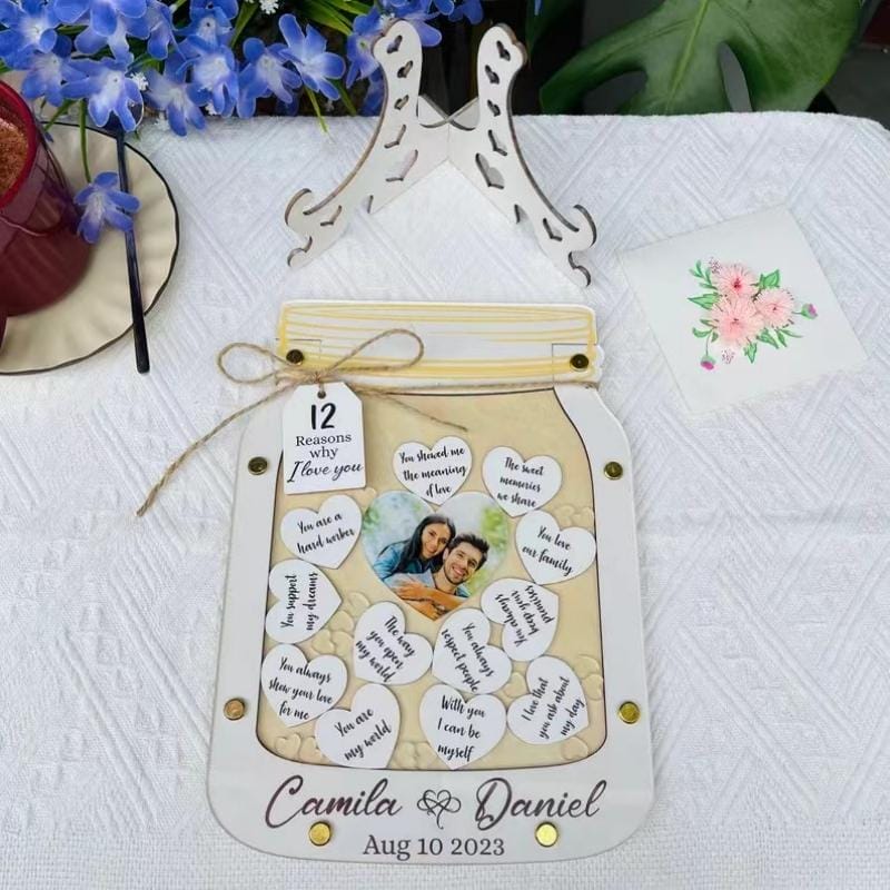 Hochzeitsgeschenk aus Holz im Einmachglas mit 12 Gründen, warum ich dich liebe, personalisiert mit den Namen des Paares und dem Datum. Herzförmige Details.