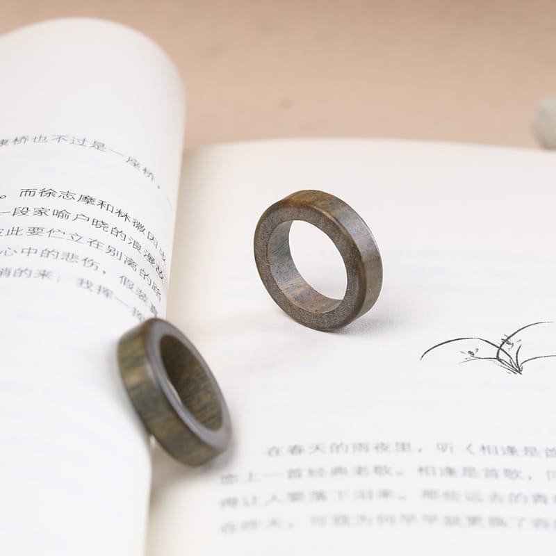 Zwei elegante Sandelholzringe auf offenem Buch. Stilvoller Holzschmuck.