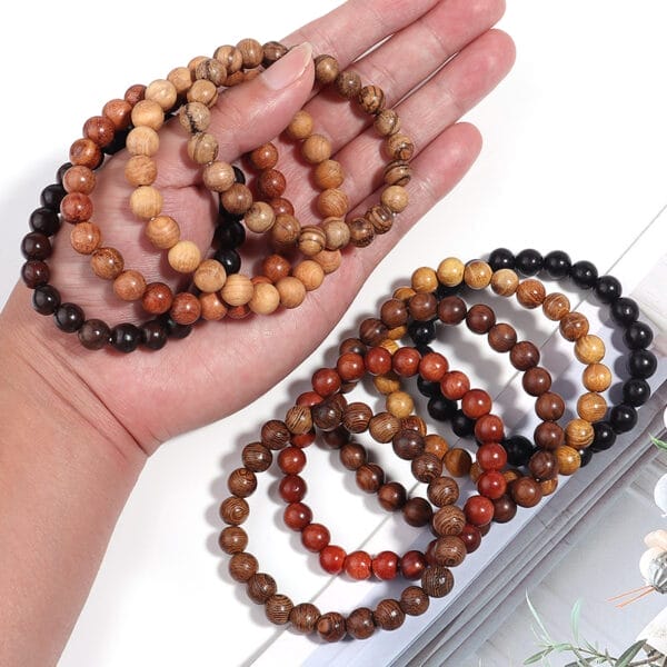 Hand hält verschiedene Armbänder aus Sandelholzperlen. Ethnisches Armband.