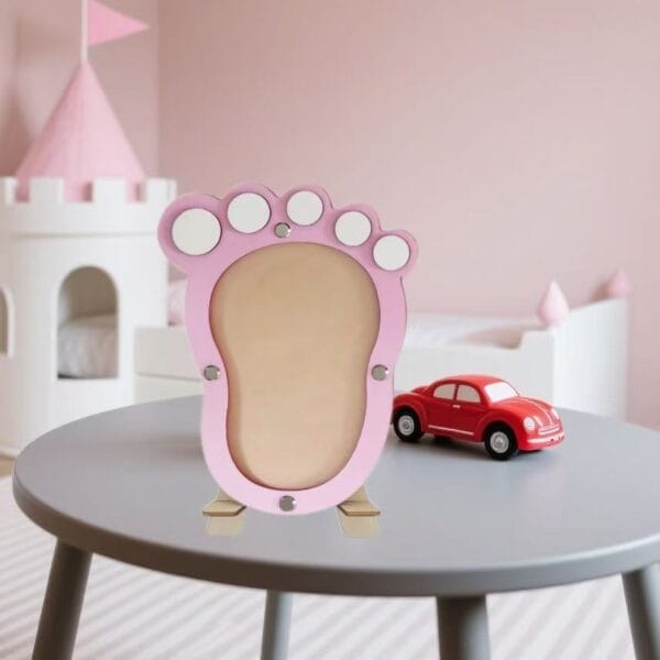 Rosafarbener Bilderrahmen aus Holz mit Baby-Fußabdrücken und kleinen Magneten. Ideales Geschenk zur Babyparty oder Taufe.