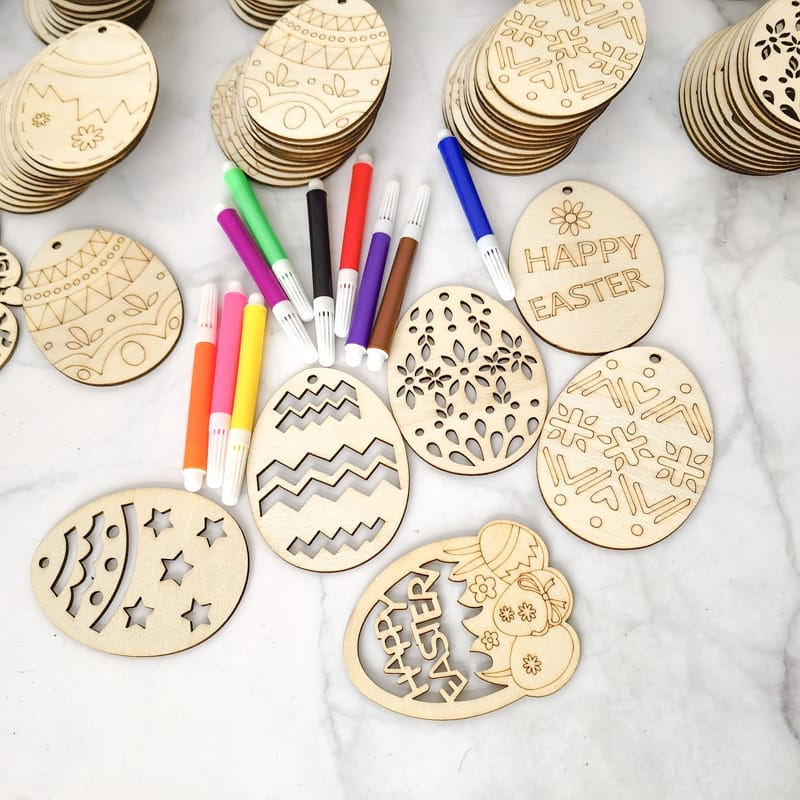 Hölzerne Ostereierformen und -marker, bereit zum Basteln für Kinder. Mit der Nachricht „Frohe Ostern“.