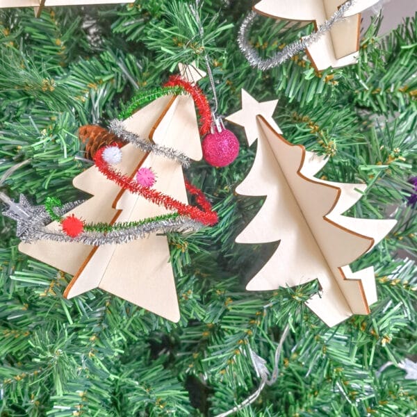 Miniatur-Weihnachtsbäume aus Holz in 3D schmücken einen geschmückten Weihnachtsbaum. Ideal zum Basteln für Kinder!