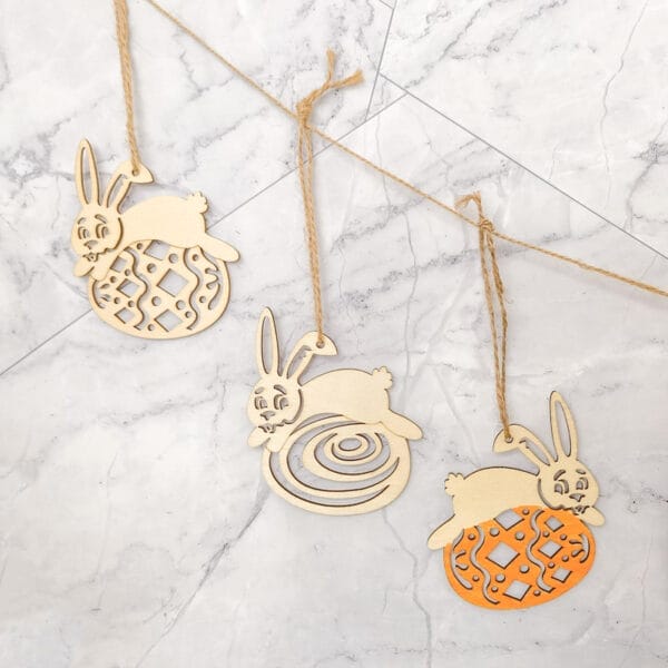 Drei hölzerne Osterhasen-Ornamente mit Juteschnur, perfekt für festliche Dekorationen. Osterhasen im Großhandel erhältlich.