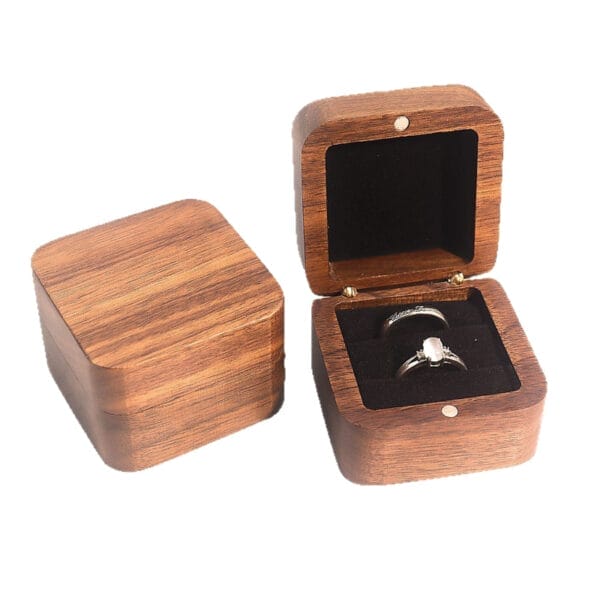Zwei Ringboxen aus Walnussholz; eine geöffnet mit zwei Ringen, die andere geschlossen. Elegante Aufbewahrung für Verlobungsringe.
