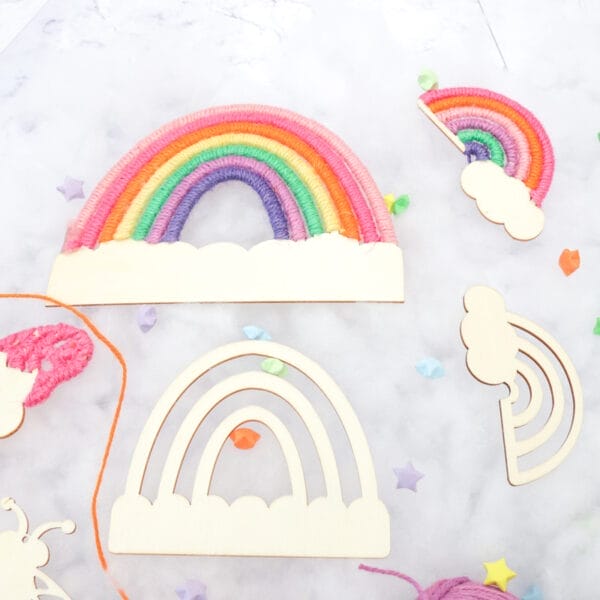 Unfertige Regenbögen und Wolken aus Holz, bereit für die DIY-Dekoration aus Juteschnur. Großhandel für Bastelbedarf aus Holzregenbögen.