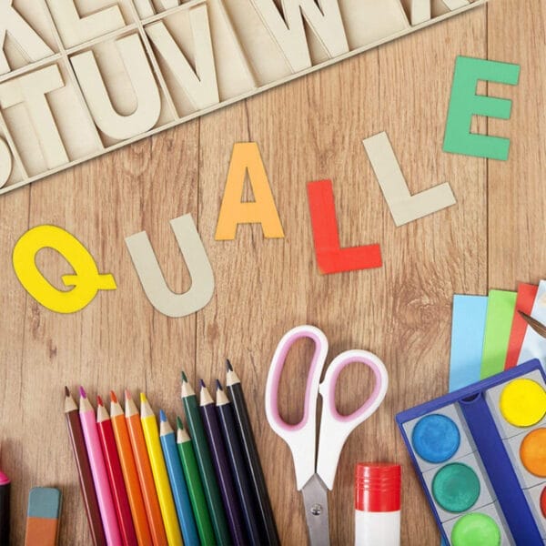 Bunte Buchstaben, die „QUALLE“ buchstabieren, mit Bastelzubehör. Holzalphabetblöcke und Künstlerbedarf für kreative Projekte.