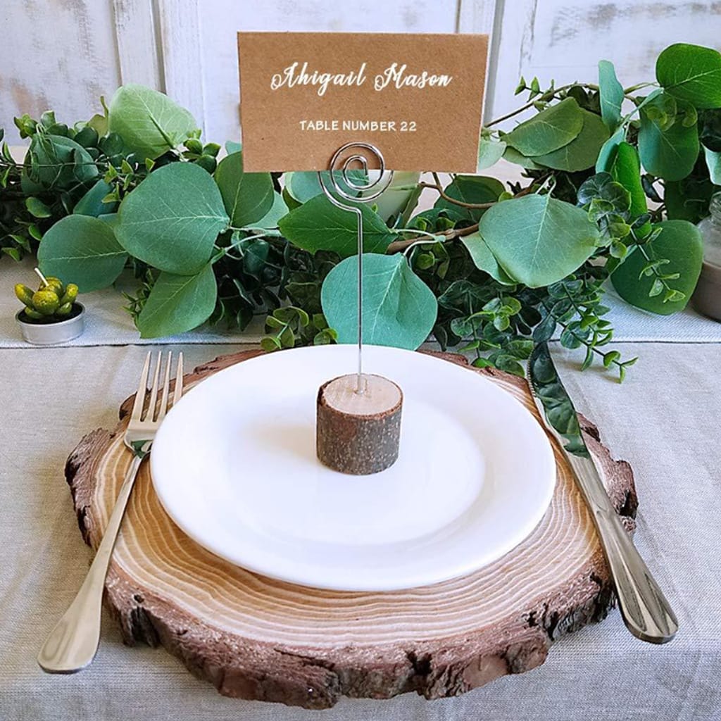 Tischkartenhalter aus Holz mit der Karte „Abigail Mason, Tischnummer 22“ bei einem rustikalen Hochzeitsempfang.