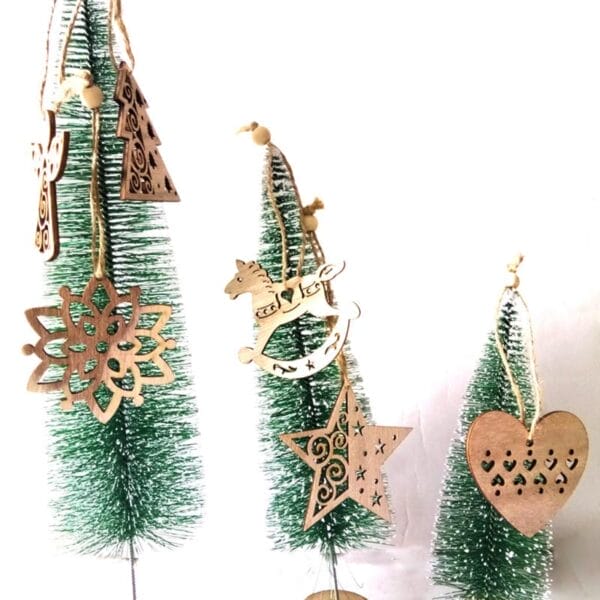 Weihnachtsschmuck aus Holz: Schneeflocke, Schaukelpferd, Stern, Engel und Herz hängen an Miniaturbäumen. Weihnachtsdekorationen im Großhandel.