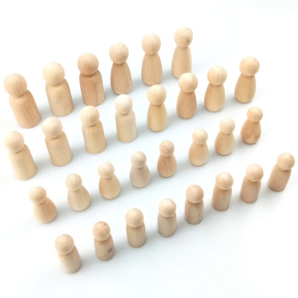 Viele kleine, unbemalte Holzpuppen auf weißem Untergrund. Ideal zum Basteln.