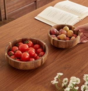 Zwei Holzschüsseln mit Tomaten und Pflaumen auf einem Holztisch. Salatschüssel Holz.