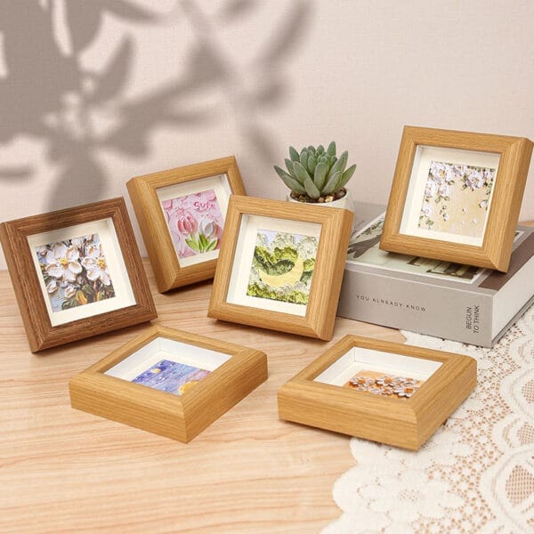 Sechs kleine, quadratische Holzbilderrahmen zeigen verschiedene Blumen- und Landschaftsdrucke. Miniatur-Holzrahmen im Großhandel.