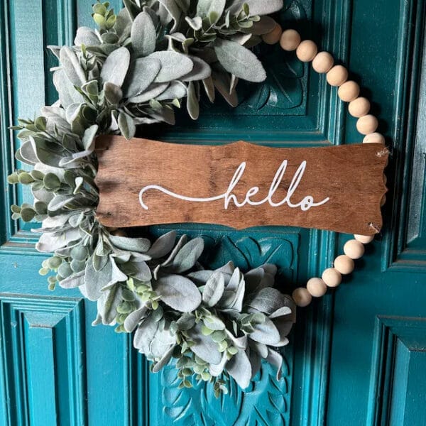 Kranz aus Holzperlen mit Lammohrgrün und „Hallo“-Schild. Elegante Tür- oder Wanddekoration.