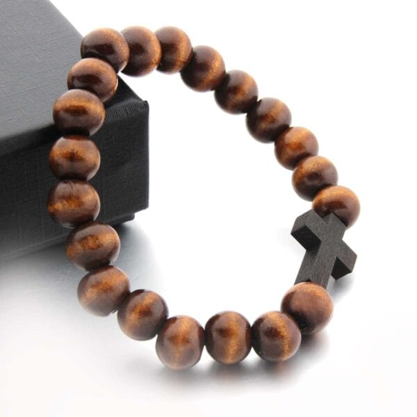 Braunes Holzperlenarmband mit einem Kreuzanhänger aus dunklem Holz. Großhandelsarmband aus Holz.