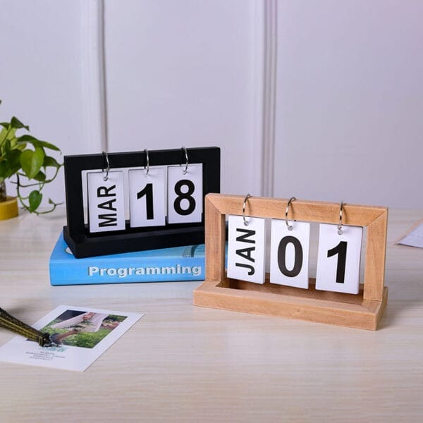 Zwei minimalistische ewige Holzkalender, einer in Schwarz, einer in Hellholz, zeigen den 18. März und den 1. Januar an. Holzkalender im Großhandel.
