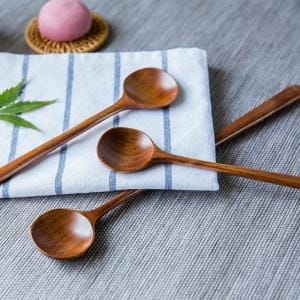 Drei dunkelbraune Holzlöffel mit langen Griffen.