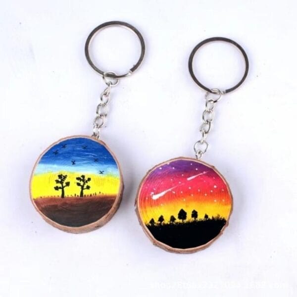 Zwei handgefertigte Schlüsselanhänger aus Holz mit gemalten Sonnenuntergangs- und Nachthimmelszenen. Runde Schlüsselanhänger aus Holz im Großhandel.