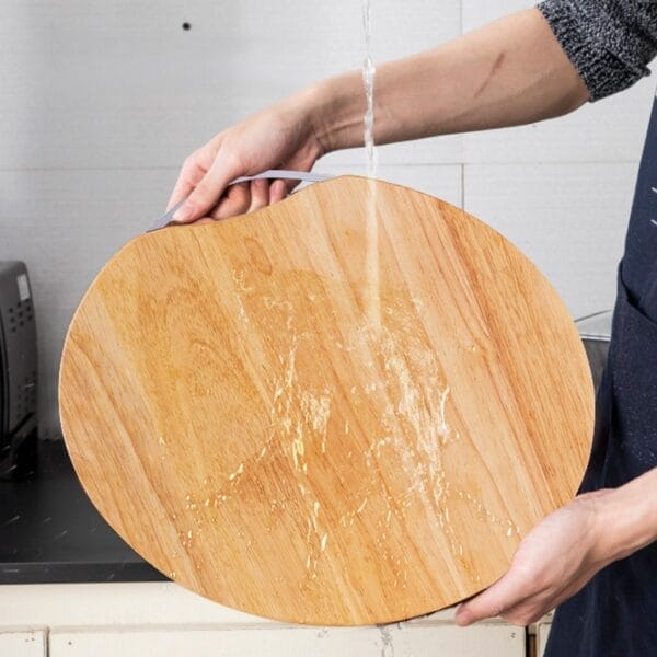 Person wäscht ein rundes, umweltfreundliches Holzschneidebrett. Großhandel mit Holzschneidebrettern.