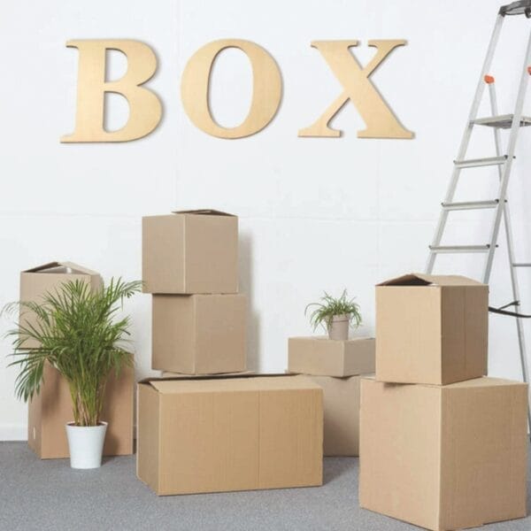 Große hölzerne BOX-Buchstaben an der Wand über Umzugskartons. 12-Zoll-Großhandelsbuchstaben.