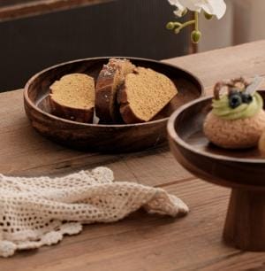 Dekoschale aus Holz mit Brot und Gebäck auf einem Holztisch.