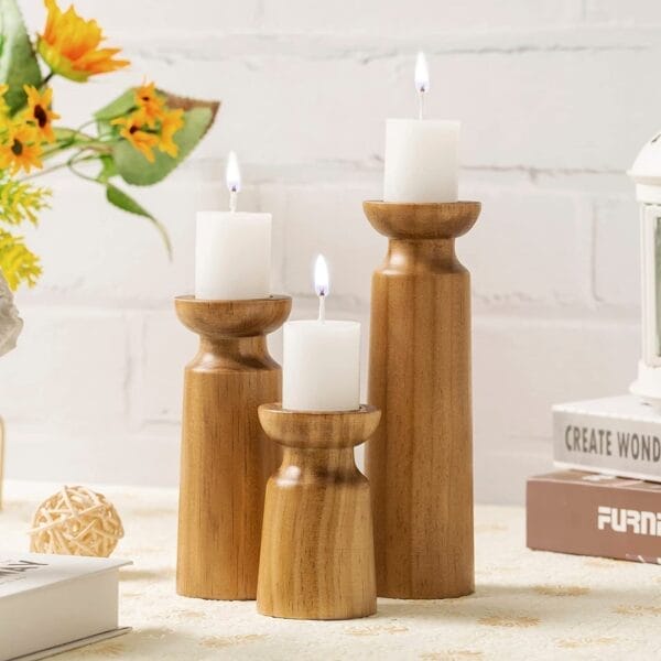 Drei hölzerne Kerzenhalter mit weißen Stumpenkerzen. Rustikale Tischdekoration aus Holz.