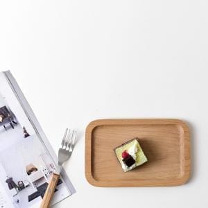 Kleines Tablett Holz mit Dessert und Gabel neben Zeitschrift.