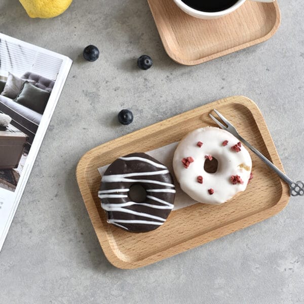 Holztablett mit zwei Donuts, einem Schokoladen- und einem weißen. Kleines Serviertablett aus Buchenholz.