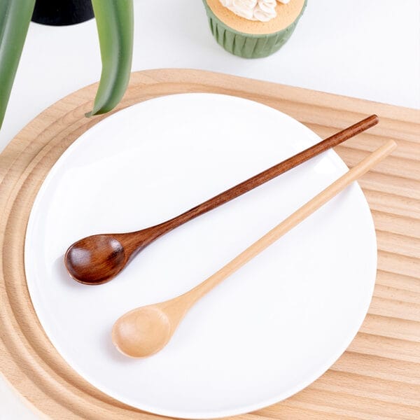 Zwei Holzlöffel mit langem Griff auf einem weißen Teller. Ideal für Kaffee oder Tee.