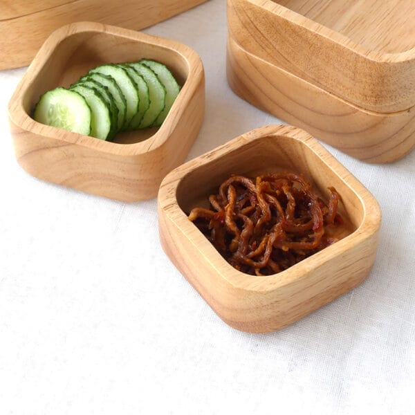 Holzschalen gefüllt mit Gurkenscheiben und gewürzten Speisen. Stilvolle und praktische Servierschalen für Snacks und Obst.