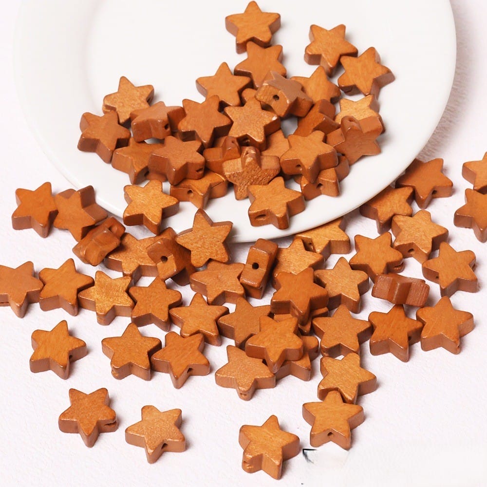 Holzsternperlen in Braun, verstreut auf einer weißen Platte und Oberfläche. Großhandelsperlen mit fünfzackigen Sternen zum Basteln.
