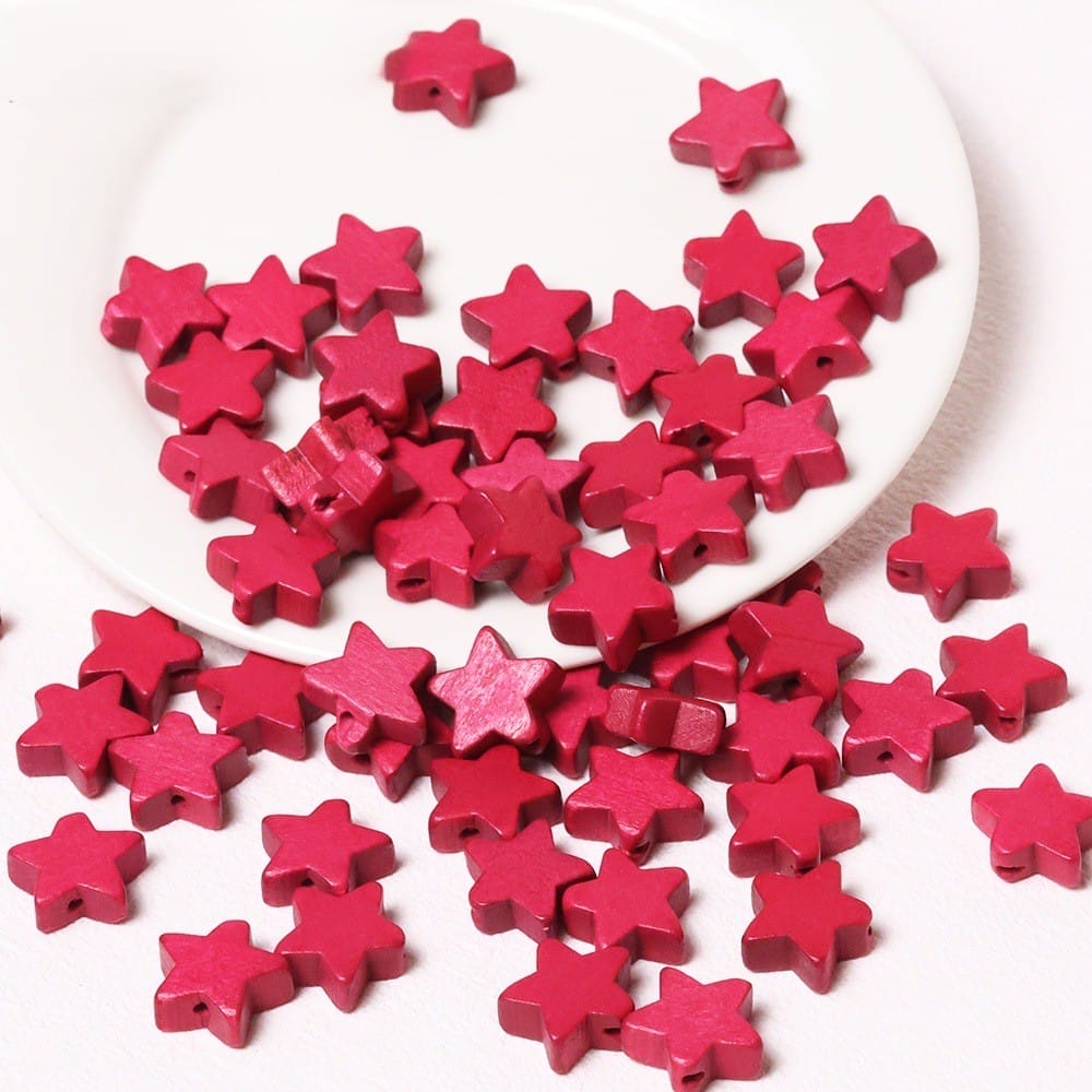 Rote Holzsternperlen auf einem weißen Teller verstreut. Fünfzackige Sternperlen im Großhandel zum Basteln.