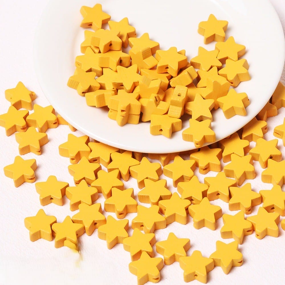 Gelbe Holzsternperlen auf einem weißen Teller. Großhandelsperlen mit fünfzackigen Sternen zum Basteln.