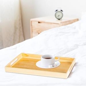 Holztablett mit Kaffee und Zuckerwürfeln auf einem Bett. Tabletts aus Holz.