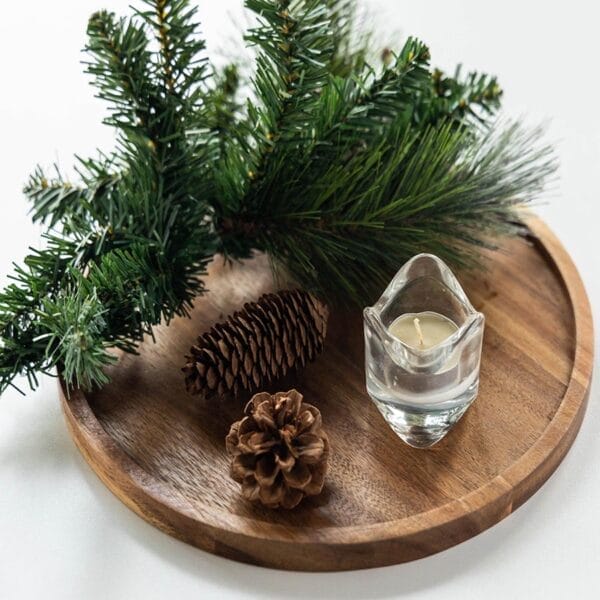 Rundes Holztablett mit Tannenzweigen, Tannenzapfen und einer Kerze. Stilvolles Serviertablett aus Akazienholz.