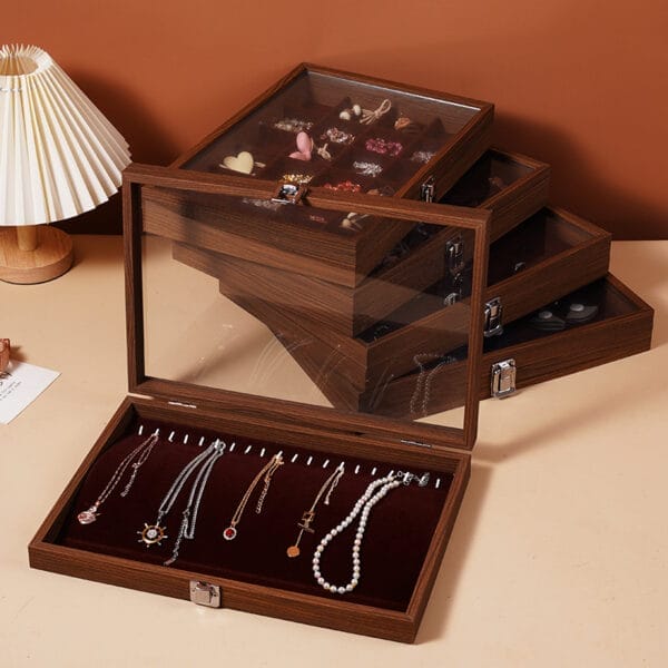 Gestapelte Schmuckkästchen aus Walnussholz mit Glasdeckeln, in denen Halsketten und Ohrringe ausgestellt sind. Ideal zur Aufbewahrung von Schmuck.
