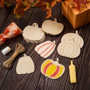 Sechs unfertige Kürbisornamente aus Holz, Bindfaden und Markierungen für DIY-Bastelarbeiten im Herbst.