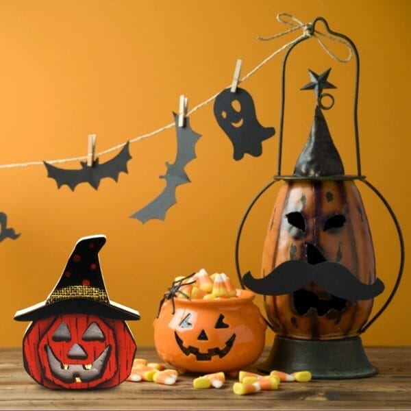 Halloween-Dekorationen: Kürbislaterne aus Holz, Maisbonbons und gruselige Silhouetten.