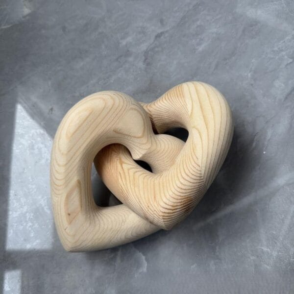 Ineinander verschlungene Holzherzen, perfekt als hölzerne Hochzeitsdeko. Romantische Holzknoten-Deko.